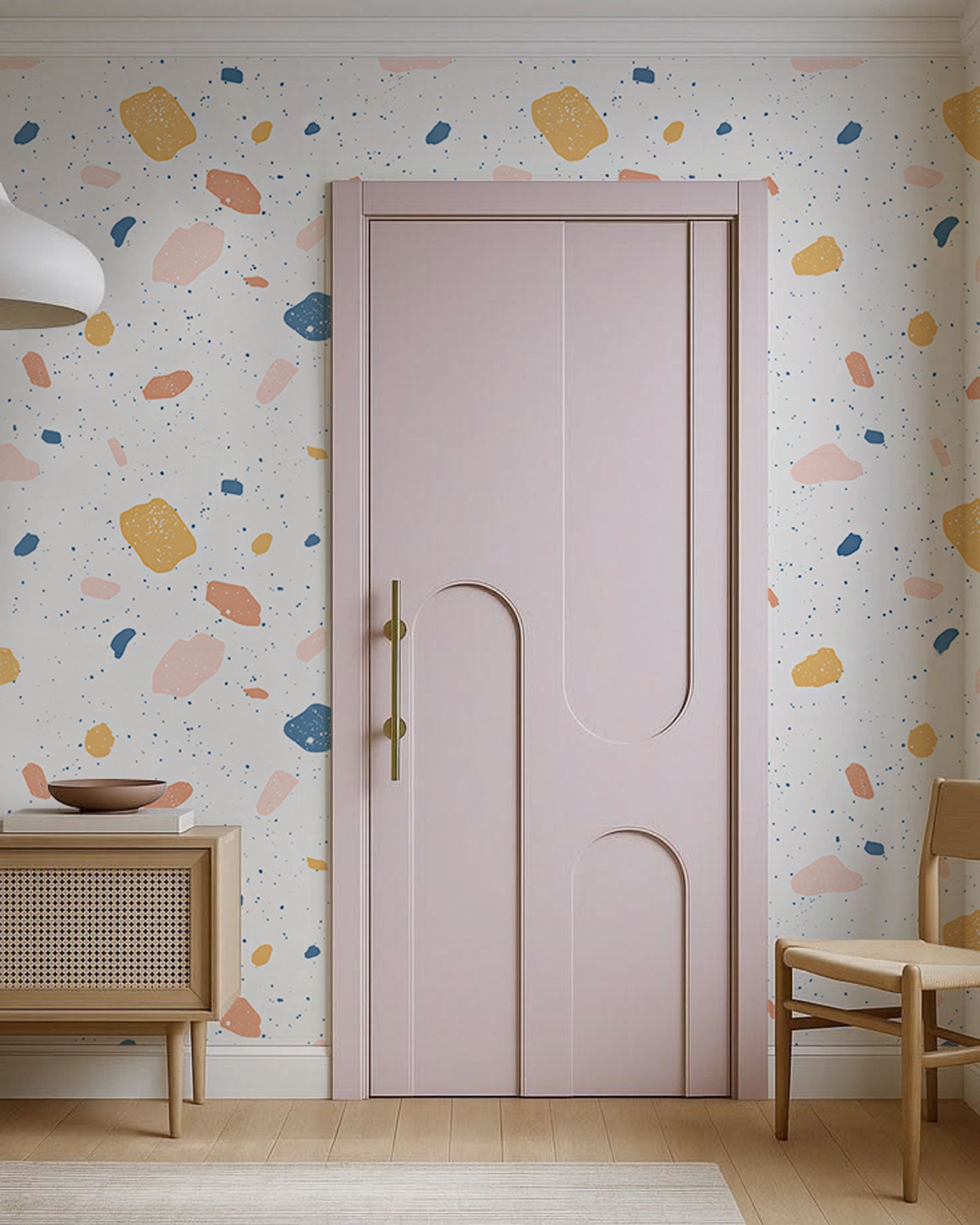 Terrazzo-style wallpaper with pastel confetti shapes in pink, blue, and ochre on a light neutral background